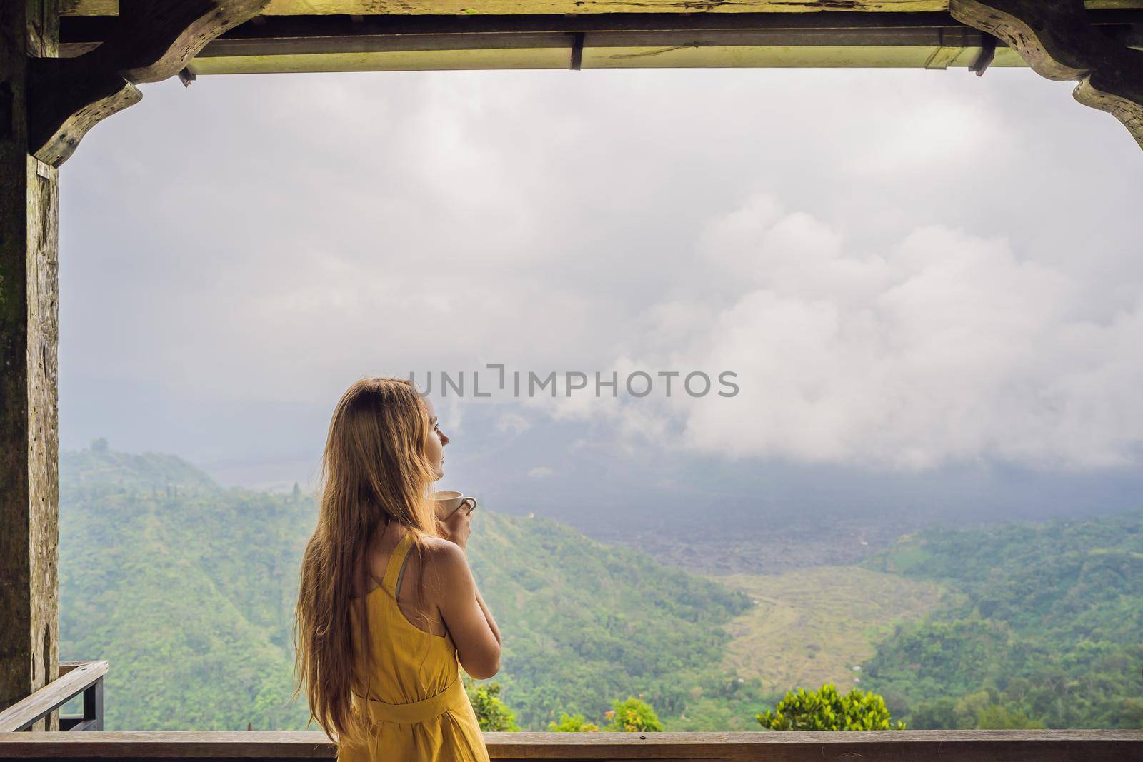 Young woman drinks coffee in a cafe in the mountains.