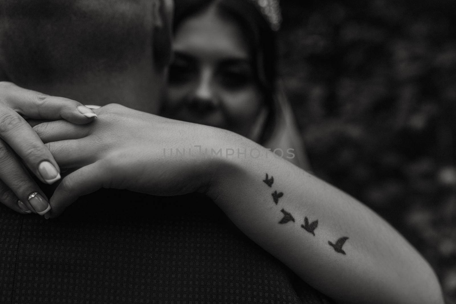 bride hugs groom arm tattoo in the form of flying birds swallows by AndriiDrachuk