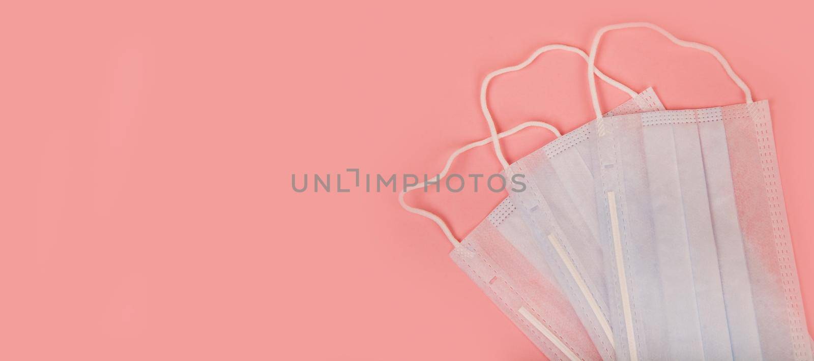 Medical mask for protection against flu and coronavirus on a pink background. Prevention of the spread of the virus and the pandemic COVID-19.