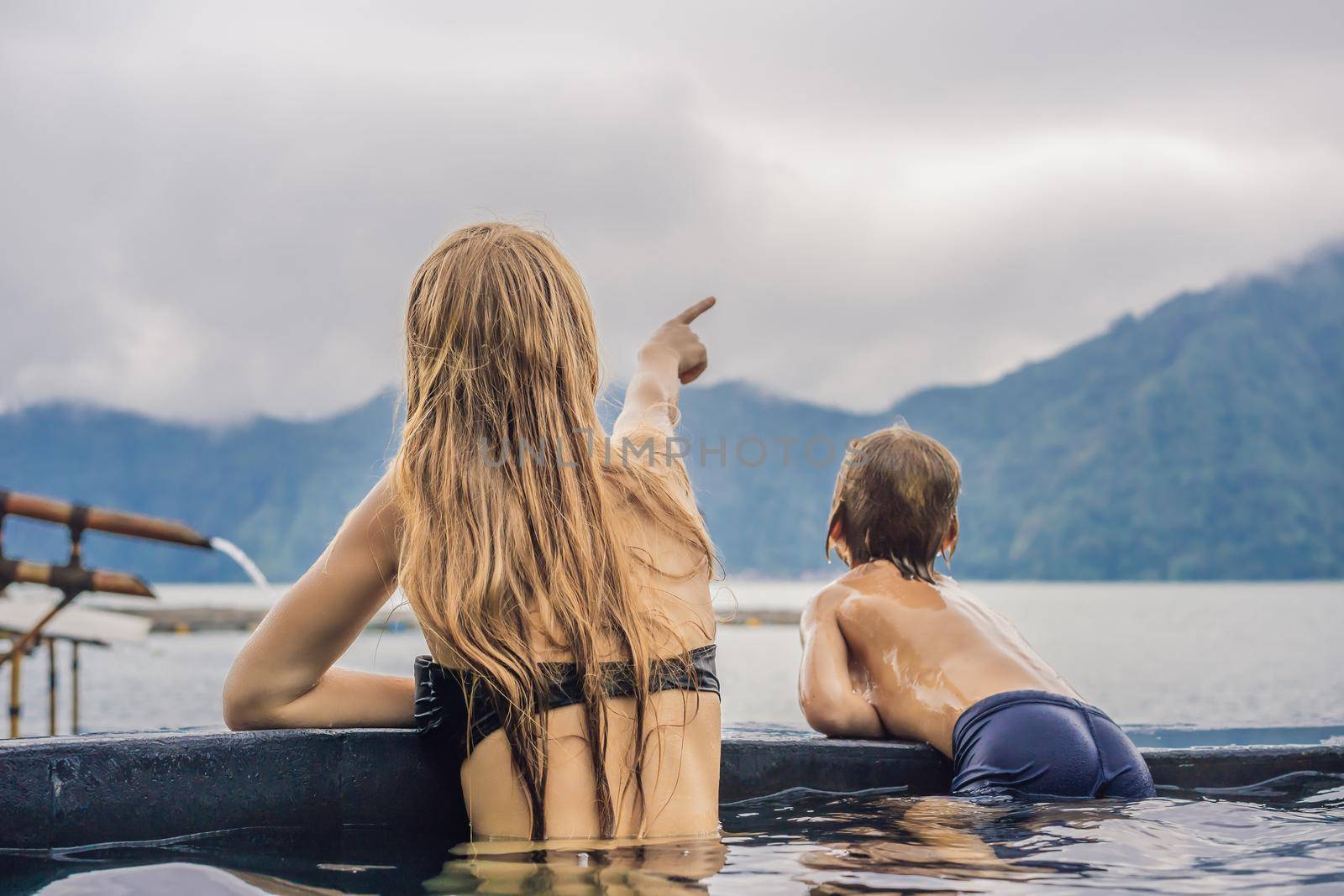 Mom and son travelers in Hot Springs in Bali on the background of lake. Traveling with children concept by galitskaya