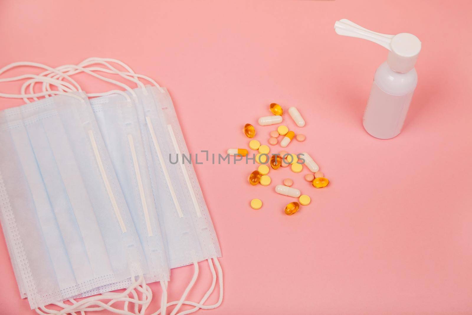 Medical mask, pills and spray for the treatment of throat on a pink background, concept of coronavirus virus and health. Medical concept. View from above.