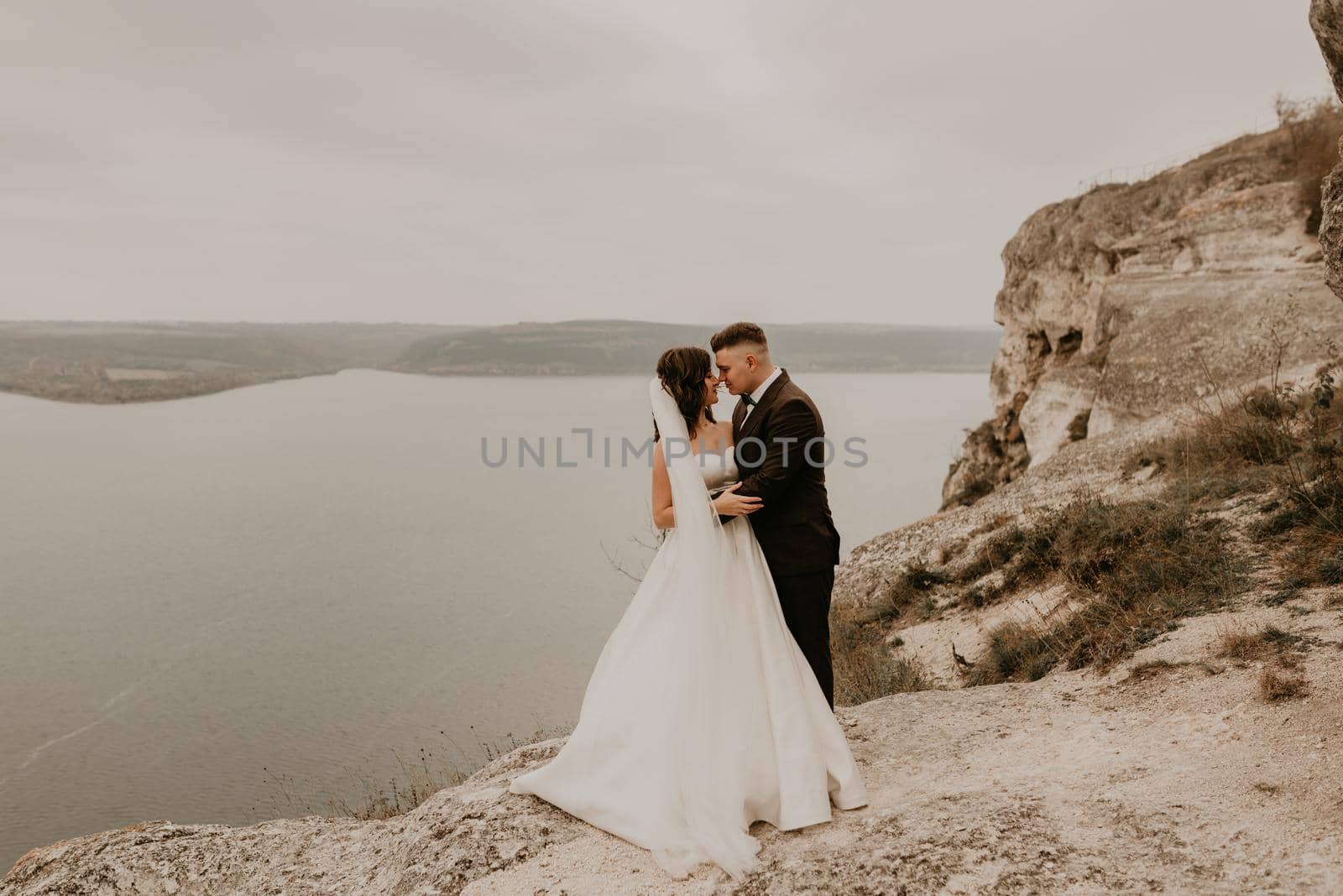 couple wedding bride groom man and woman on rocks above cliff by AndriiDrachuk