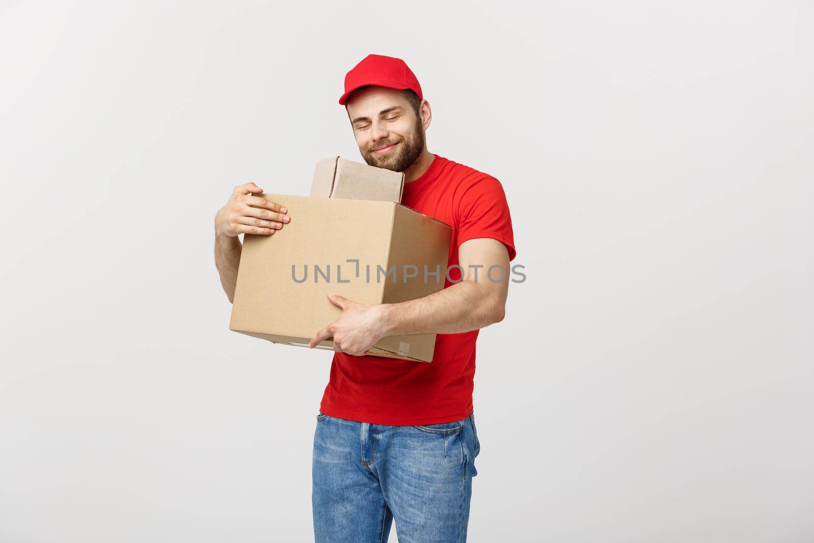 Portrait delivery man in cap with red t-shirt working as courier or dealer holding two empty cardboard boxes. Receiving package. Copy space for advertisement.