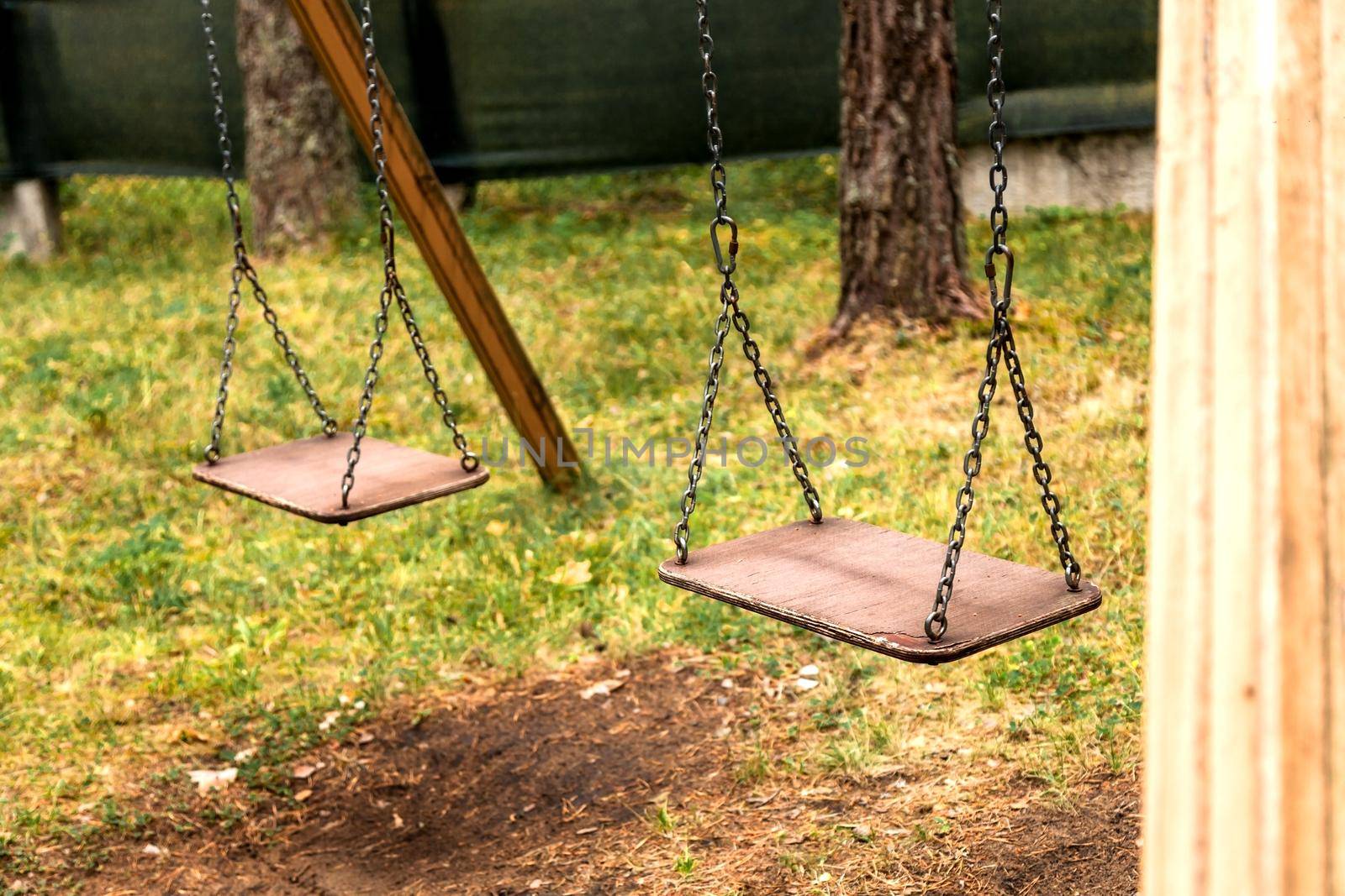 Wooden swing on a chain in a forest park