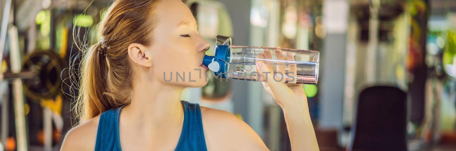 Young athletic woman drinking water in gym. BANNER, LONG FORMAT