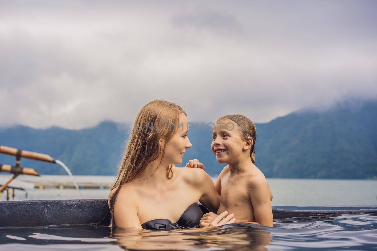 Mom and son travelers in Hot Springs in Bali on the background of lake. Traveling with children concept by galitskaya