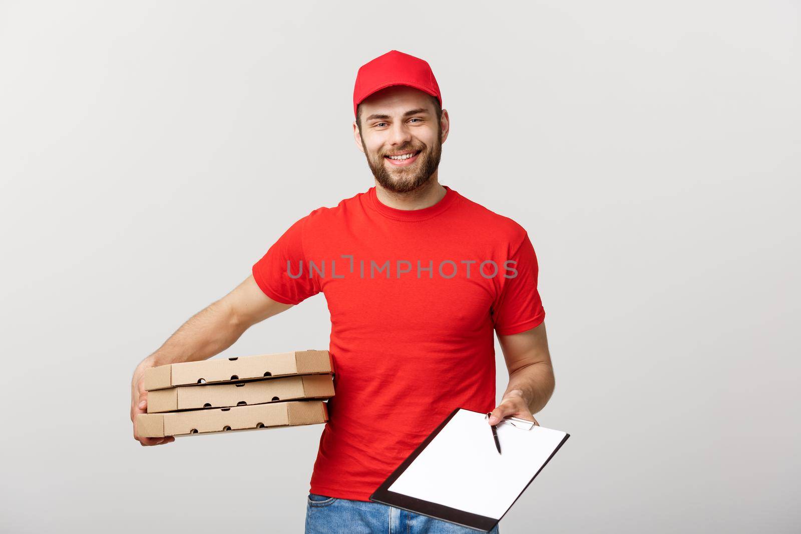 Delivery Concept: Young handsome delivery man with pizza boxes giving you a document to sign.