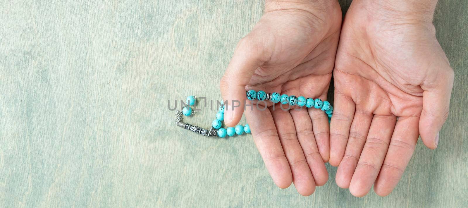 banner with top view on male hands holding rosary beads. Ramadan Kareem background. Muslim man holds a rosary. Flat lay. copy space
