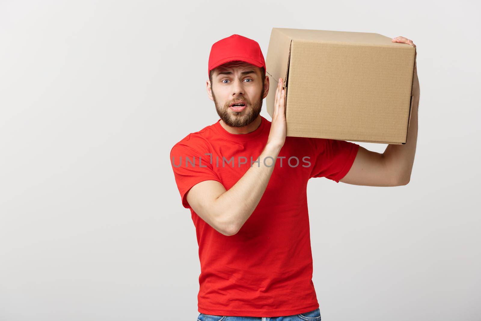 Delivery Concept: handsome Delivery man with boxes, delivery, courier with worry facial expression. Isolated grey background