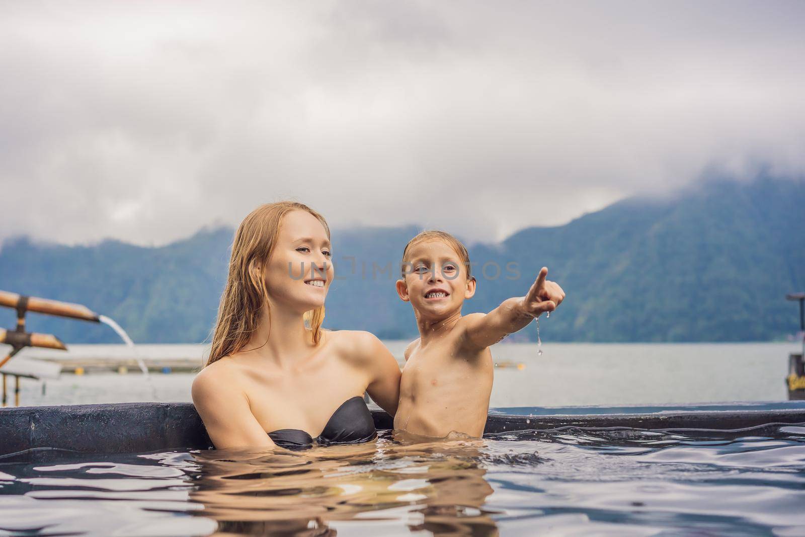 Mom and son travelers in Hot Springs in Bali on the background of lake. Traveling with children concept.