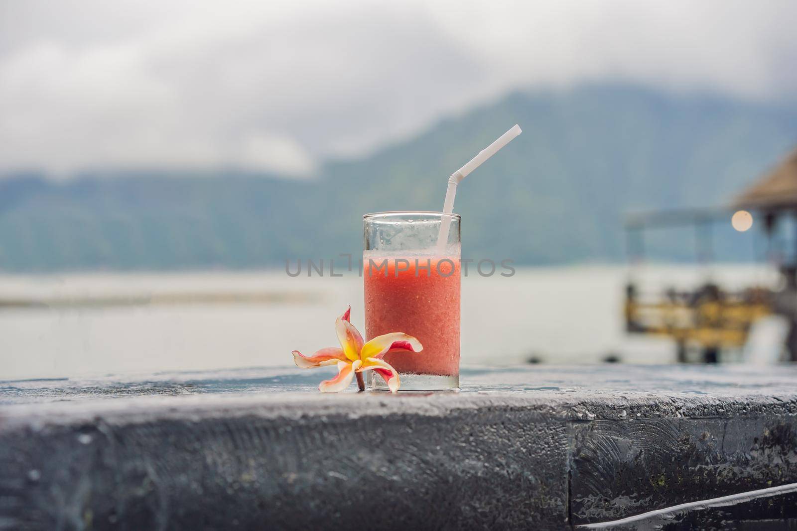 A glass of guava juice on the background of a lake and mountains. Healthy eating concept.