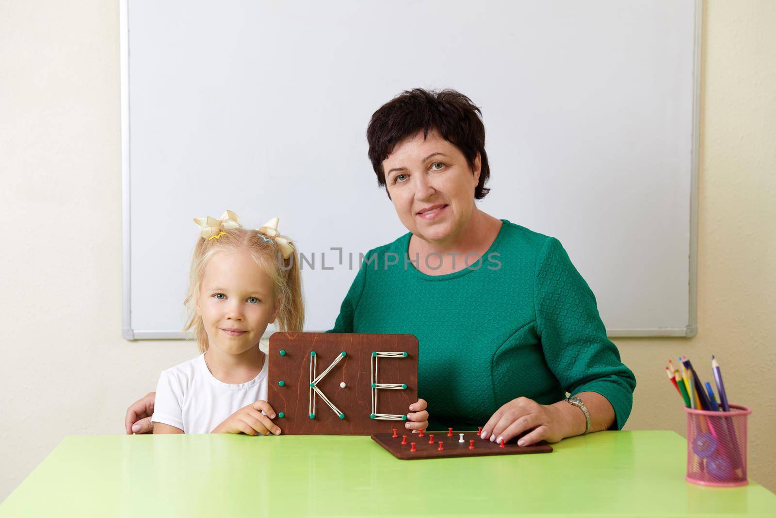 Adult woman teaches child the alphabet. Development of fine motor skills concept by Mariakray