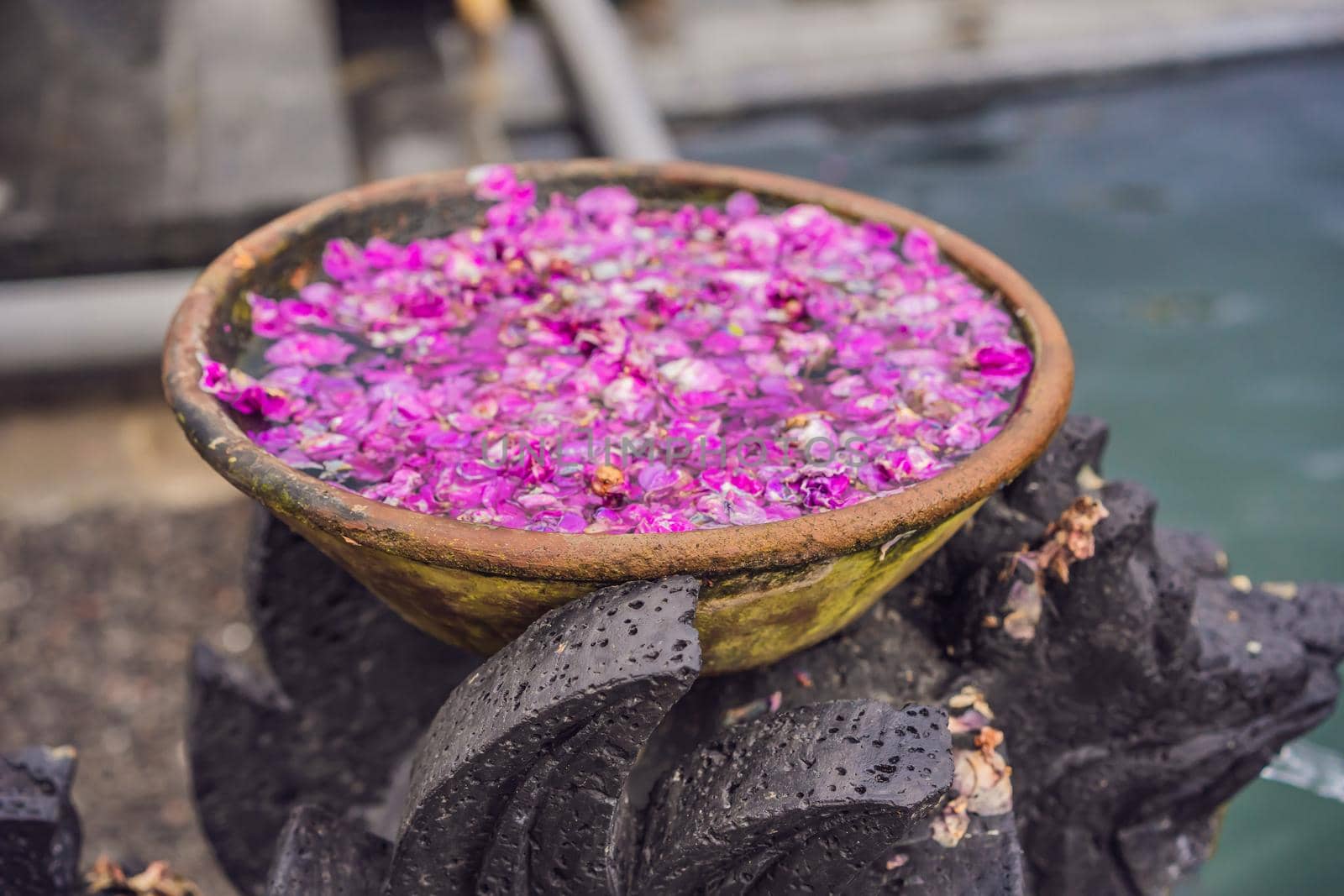 Balinese basin with flower petals on the background of the pool.