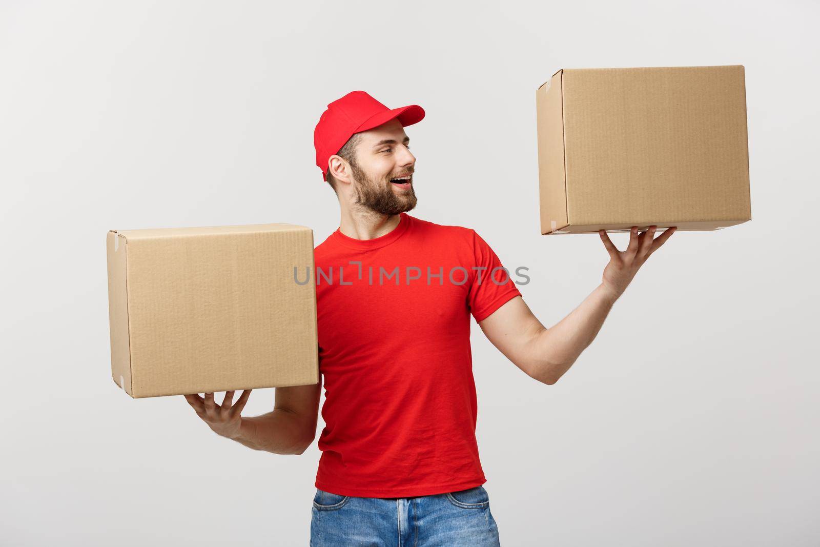 Portrait delivery man in cap with red t-shirt working as courier or dealer holding two empty cardboard boxes. Receiving package. Copy space for advertisement.