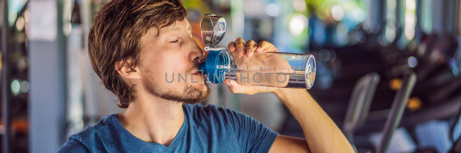 Sport man drinking water in the gym. BANNER, LONG FORMAT