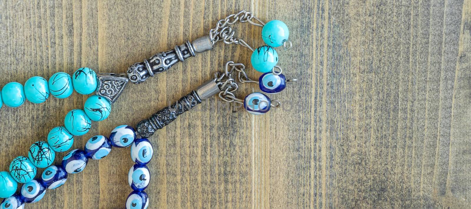 banner with two blue beads sequenced, short rosary on wooden table. tespih tesbih, an important accessory for Turkish culture. rosary beads Tasbih Islamic Muslim Stuff Prayers concept. copy space