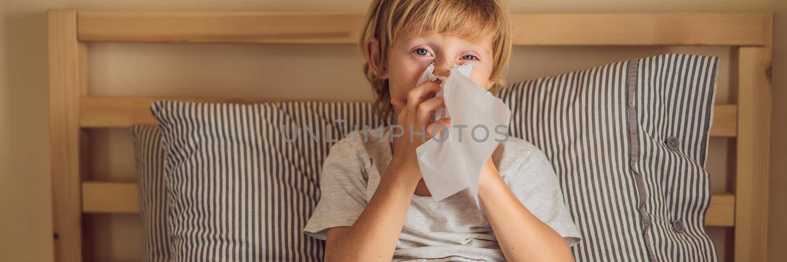Sick boy coughs and wipes his nose with wipes. Sick child with fever and illness in bed BANNER, LONG FORMAT by galitskaya
