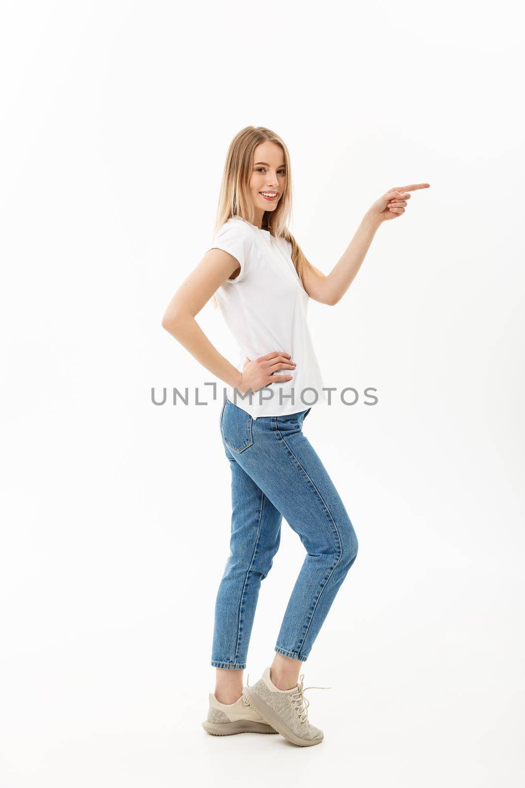 Lifestyle Concept: Portrait woman pointing or pushing something with index finger. Beautiful casual young woman isolated on white background in full length standing in profile