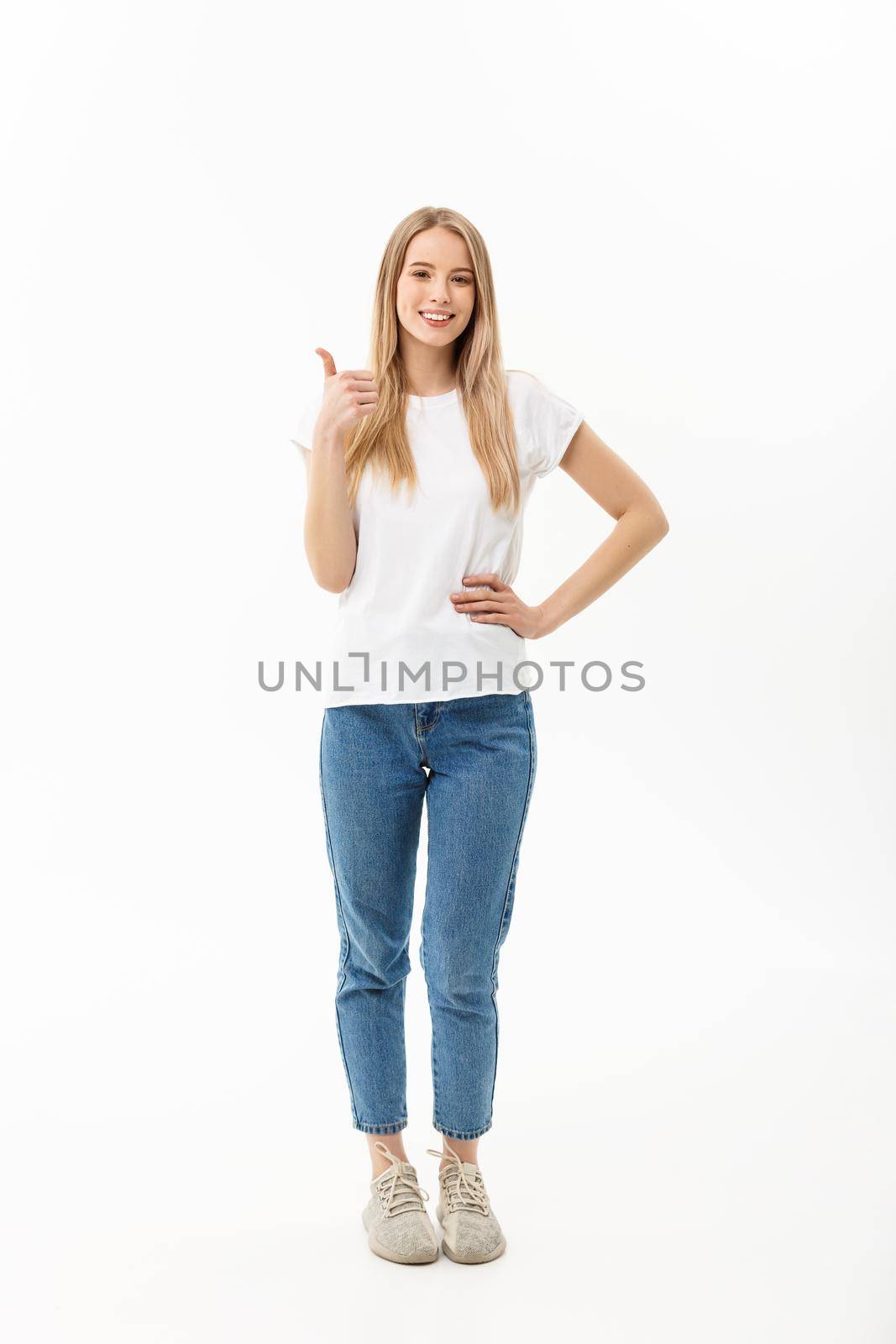 Lifestyle Concept: Happy smiling young woman in jeans looking at the camera giving a thumbs up of success and approval isolated on white by Benzoix