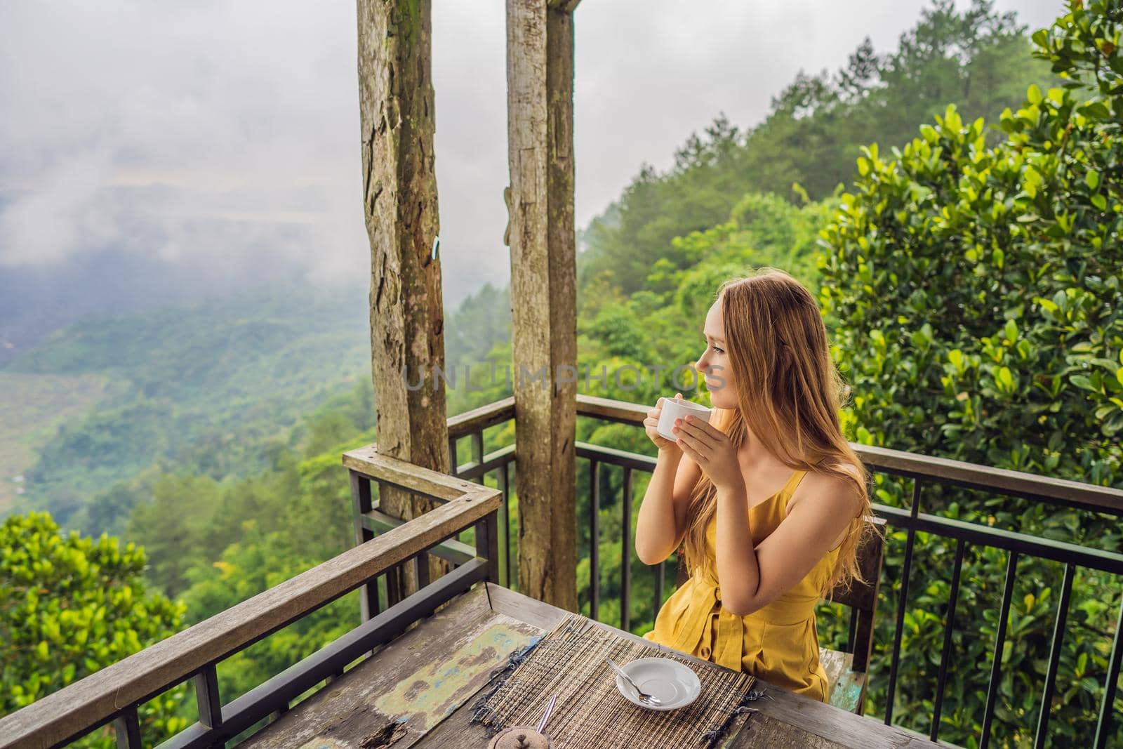 Young woman drinks coffee in a cafe in the mountains.