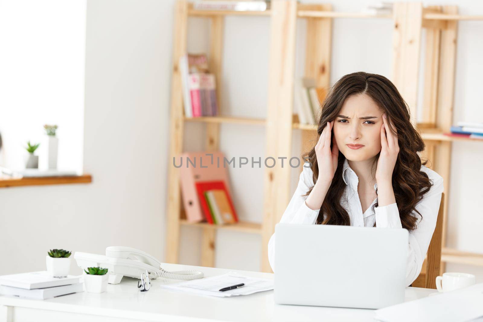 Tired young businesswoman suffering from long time sitting at computer desk in office.