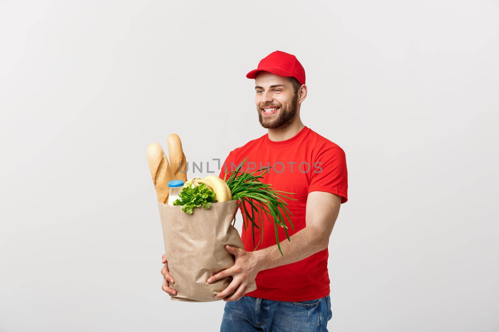 Delivery Concept - Handsome Cacasian delivery man carrying package bag of grocery food and drink from store. Isolated on Grey studio Background. Copy Space