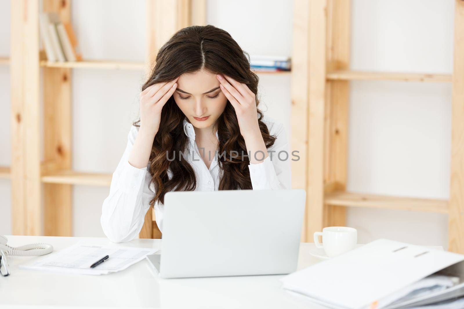 Tired young businesswoman suffering from long time sitting at computer desk in office.