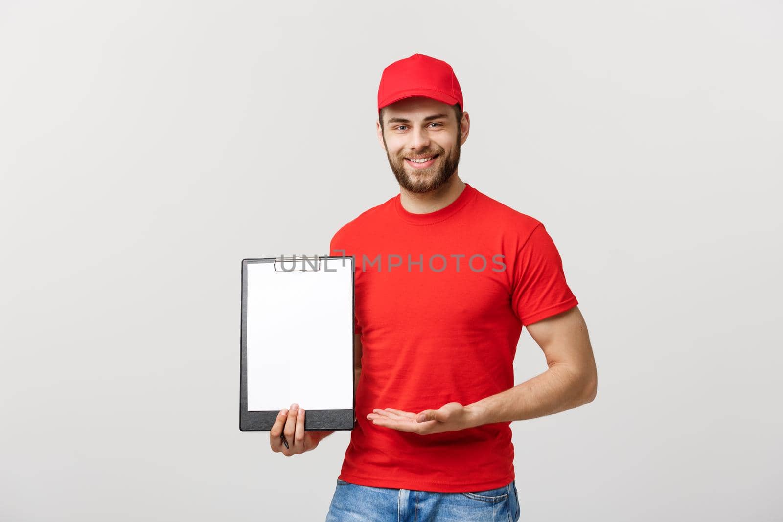 Delivery man in red uniform holding white empty blank paper isolated on white background. Copy space advertisement. Place for text or image.