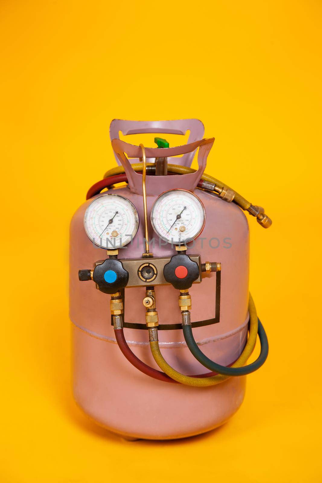 Pressure gauges measuring devices for refueling air conditioners, sensors. Cylinder with freon on a yellow background. Tools for HVAC.