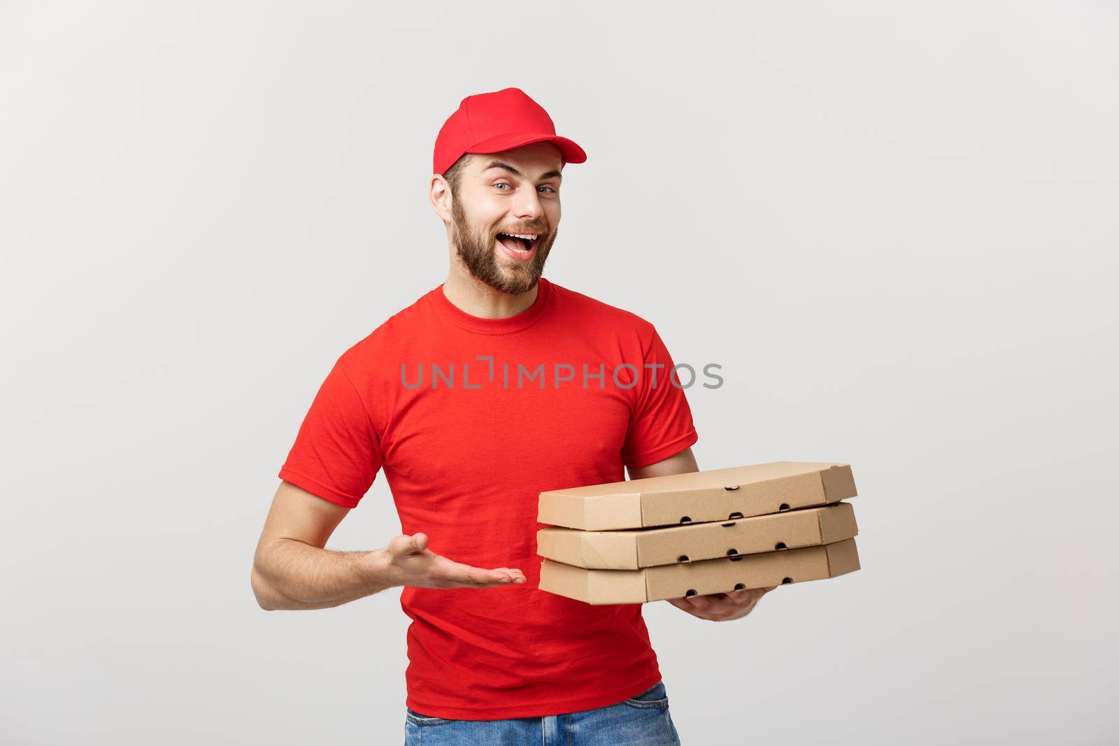 Delivery Concept: Young caucasian Handsome Pizza delivery man holding pizza boxes isolated over grey background.