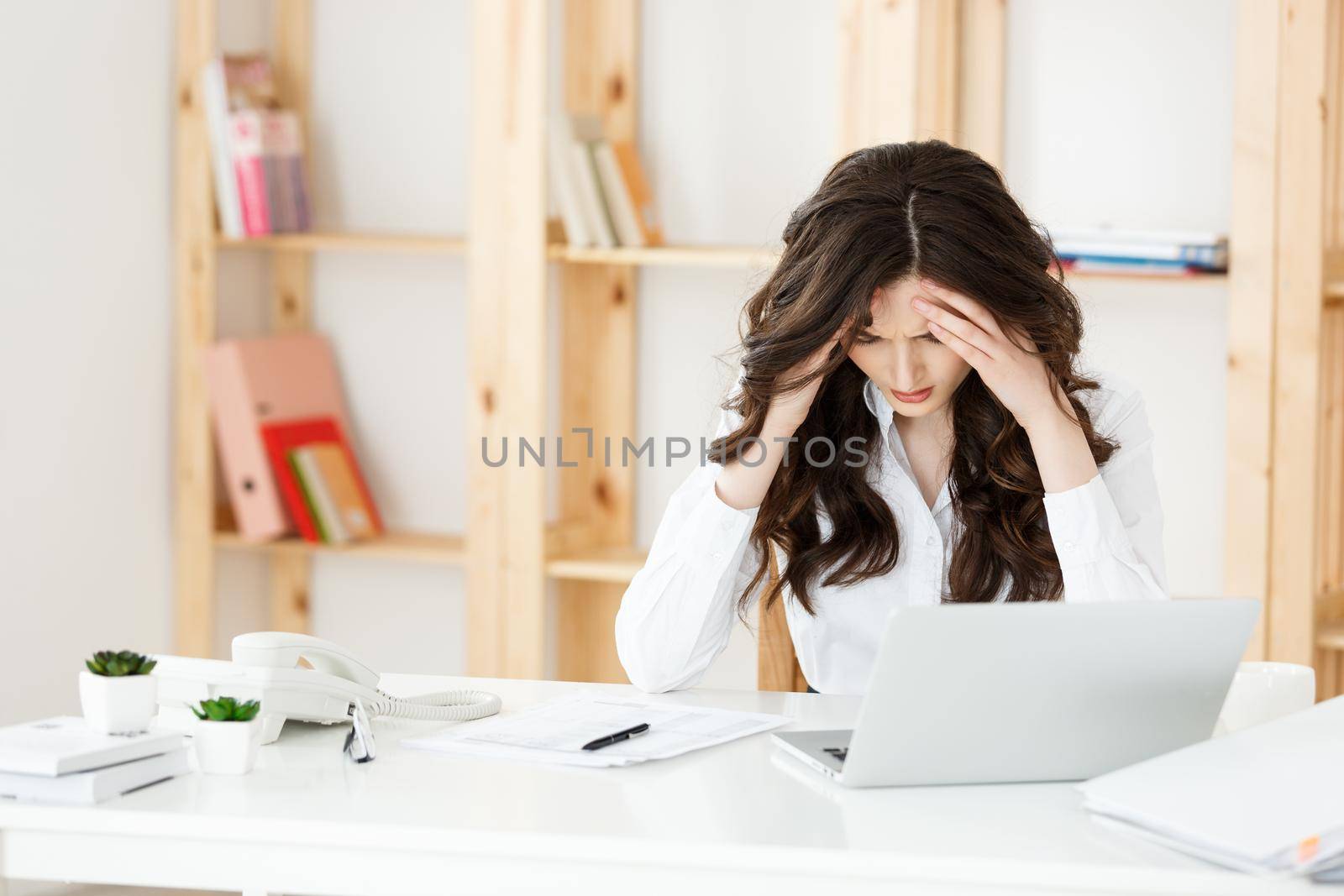 Tired young businesswoman suffering from long time sitting at computer desk in office.