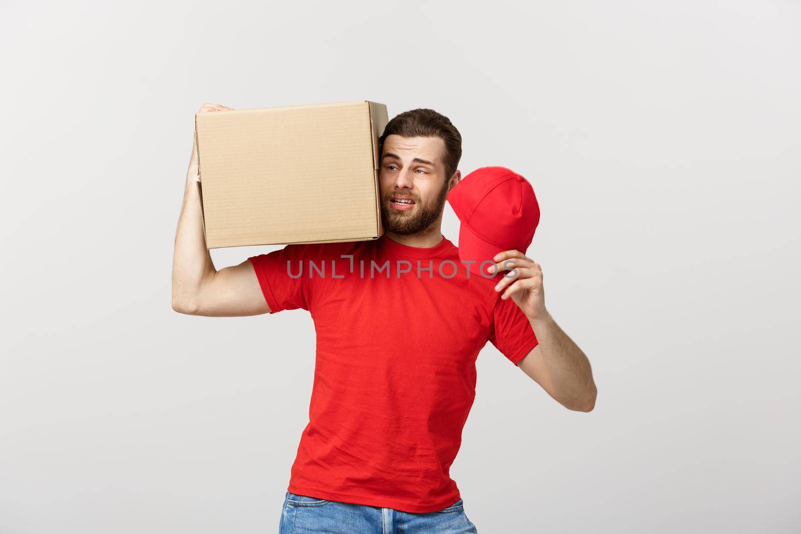 Delivery Concept: handsome Delivery man with boxes, delivery, courier with worry facial expression. Isolated grey background