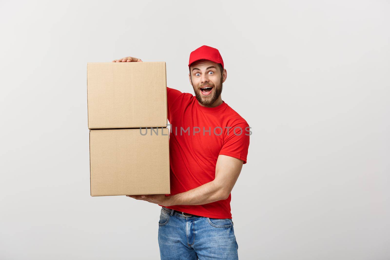 Portrait delivery man in cap with red t-shirt working as courier or dealer holding two empty cardboard boxes. Receiving package. Copy space for advertisement.