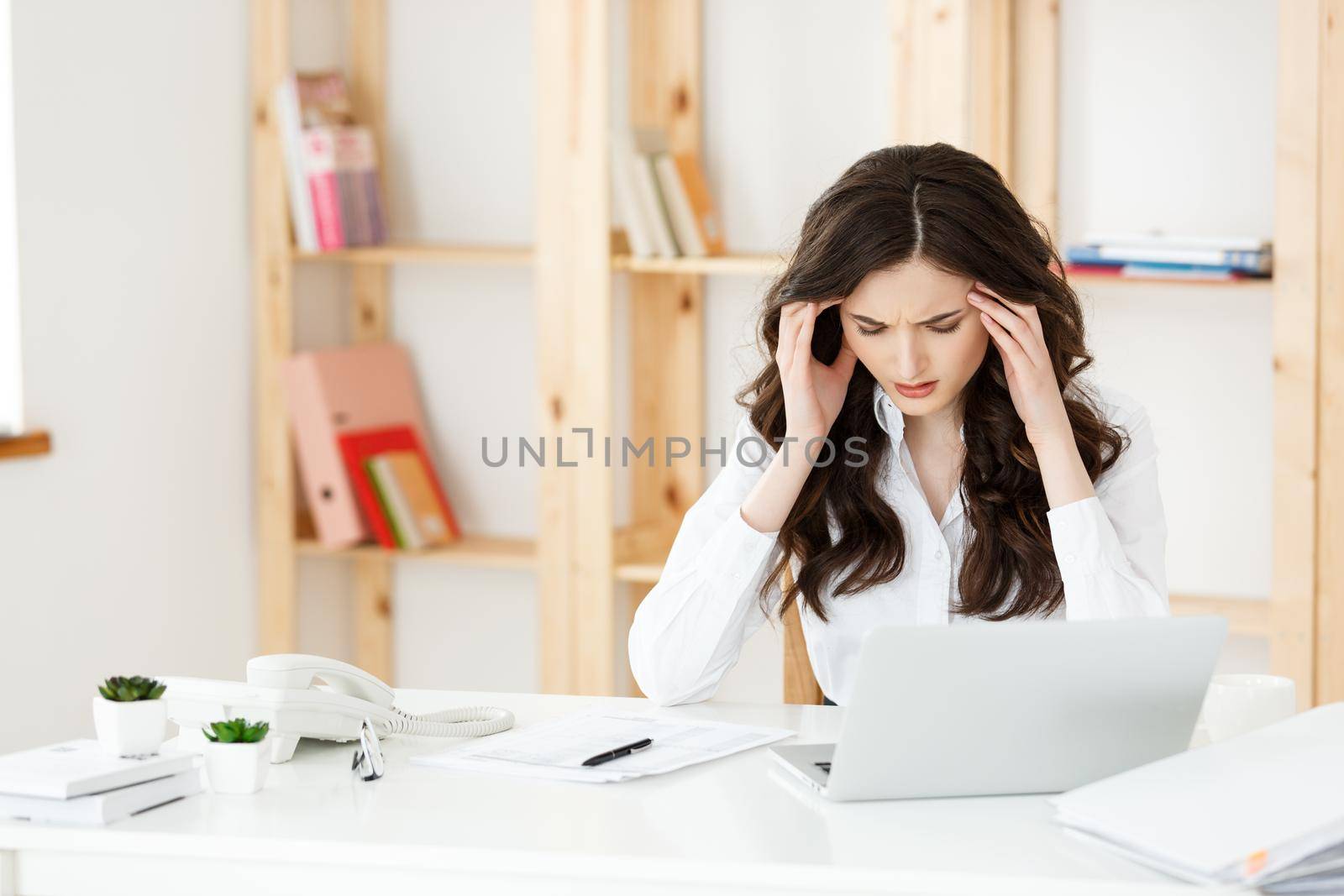 Tired young businesswoman suffering from long time sitting at computer desk in office.