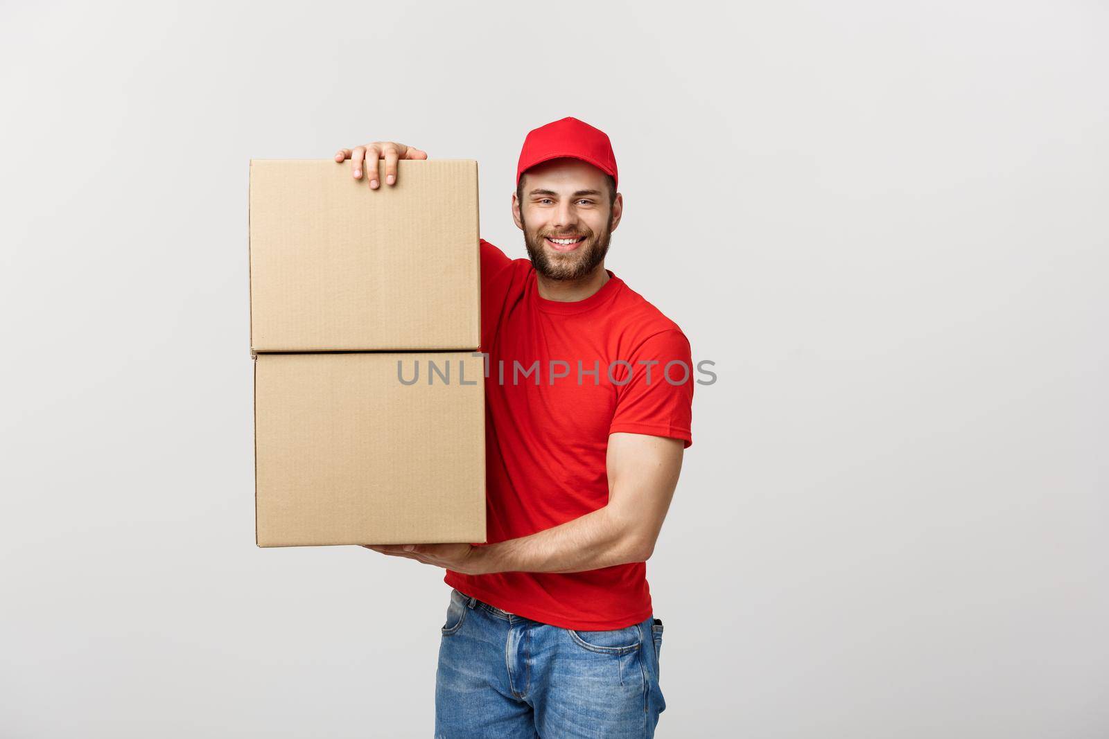 Portrait delivery man in cap with red t-shirt working as courier or dealer holding two empty cardboard boxes. Receiving package. Copy space for advertisement.