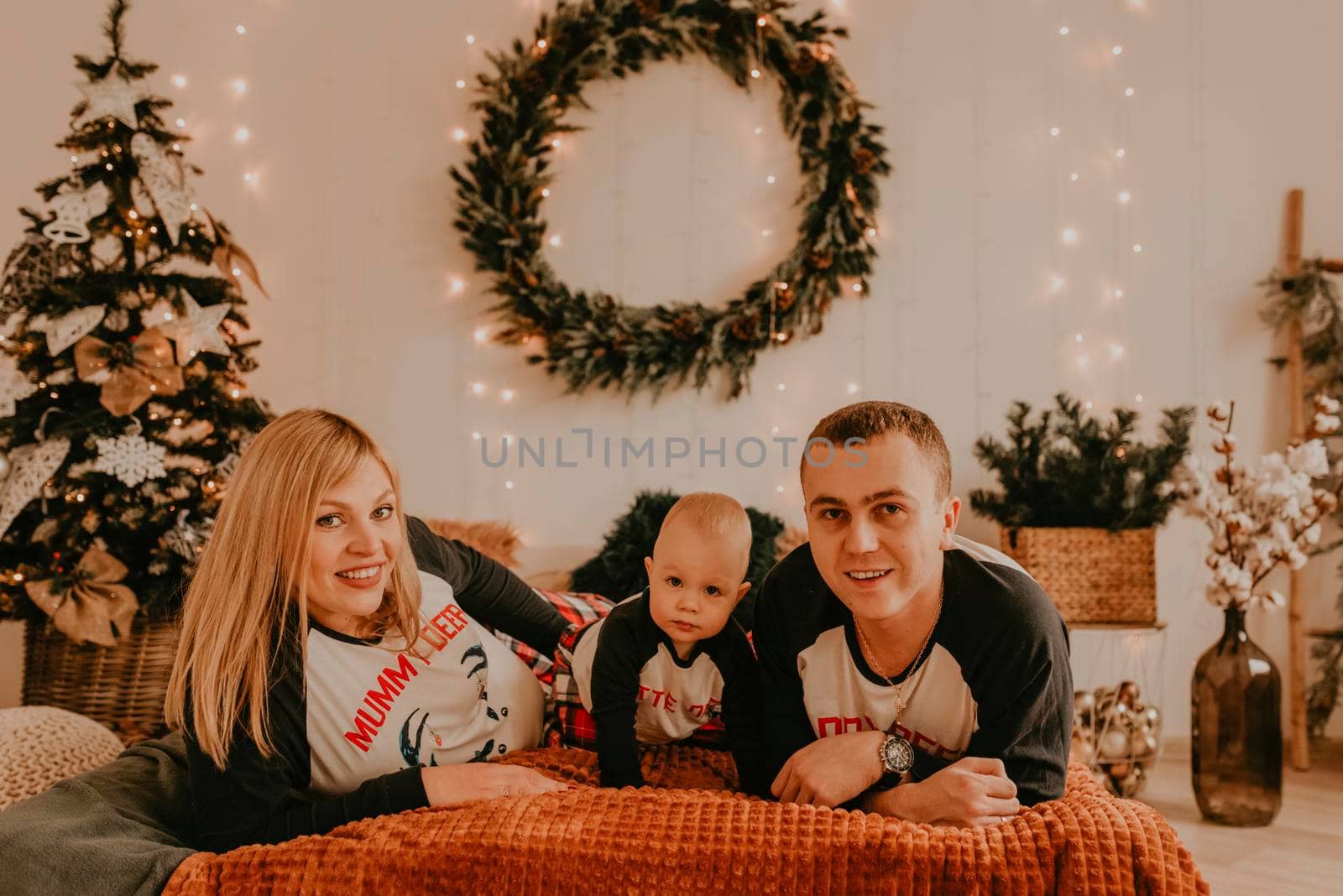 cheerful happy family in pajamas with child lie on the bed in the bedroom. new year family clothes looks outfits. Valentine's Day Celebration Gifts