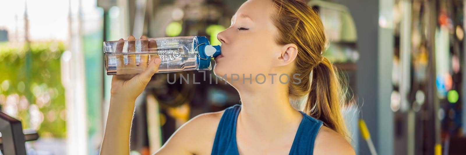 Young athletic woman drinking water in gym. BANNER, LONG FORMAT