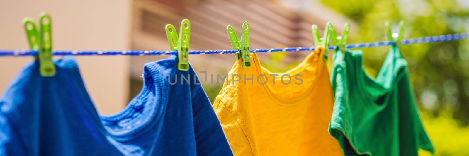 Multicolor shirts on clothesline in sunny day BANNER, LONG FORMAT by galitskaya