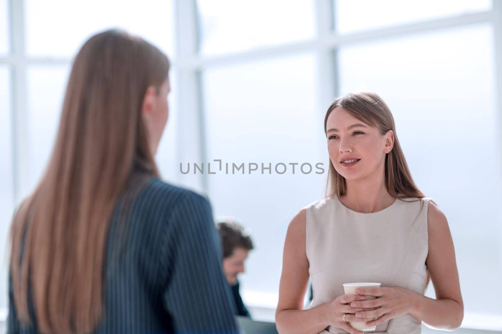 businesswoman with a glass of coffee discussing something with her colleague by asdf