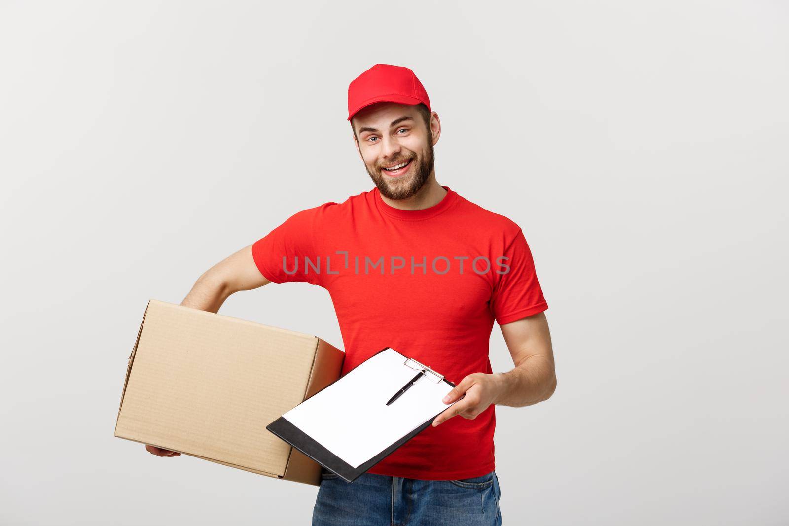Delivery Concept: Young handsome delivery man with paper boxes giving you a document to sign.