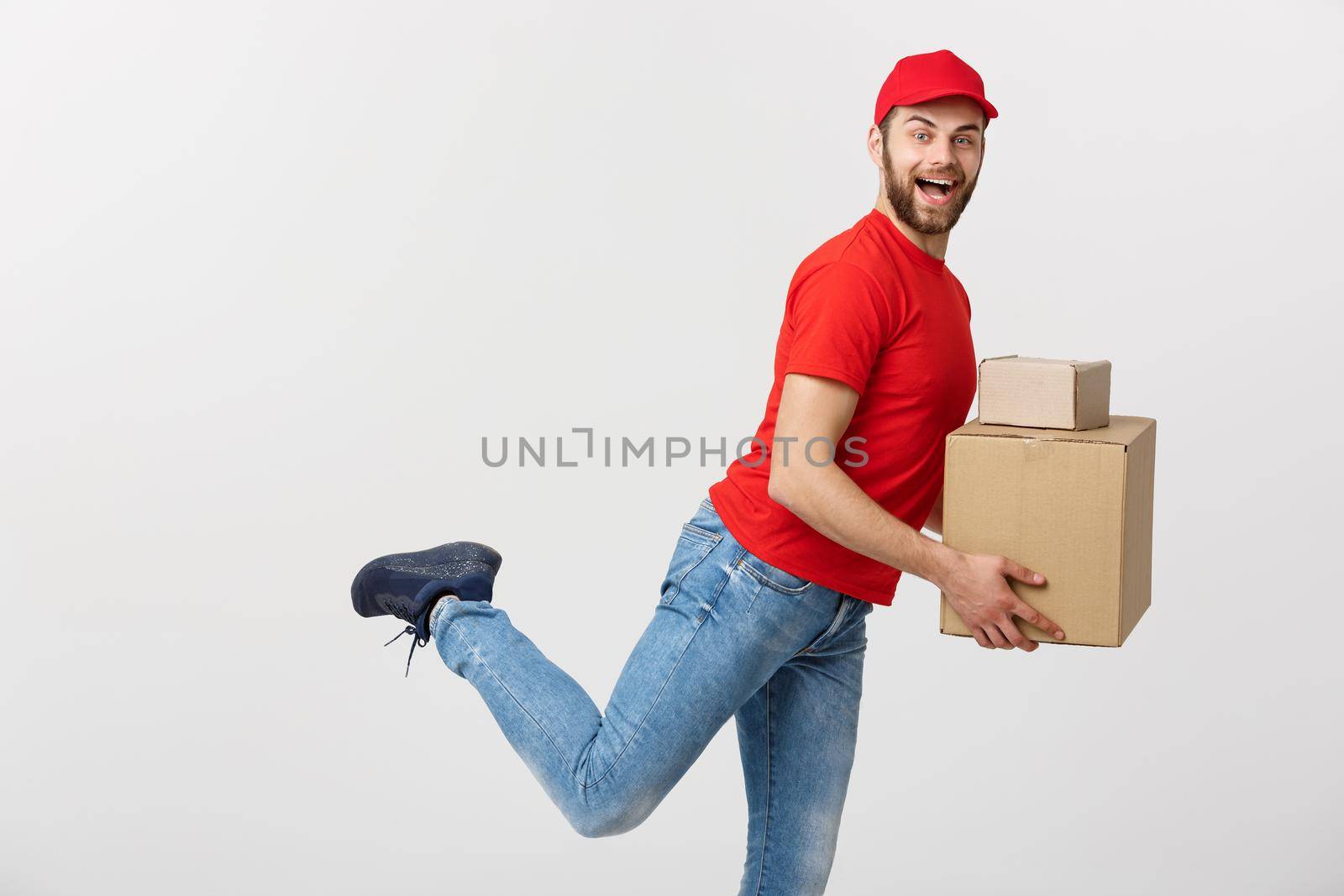 Delivery Concept - Handsome caucasian delivery man rush running for delivering a package for customer. Isolated on Grey studio Background. Copy Space