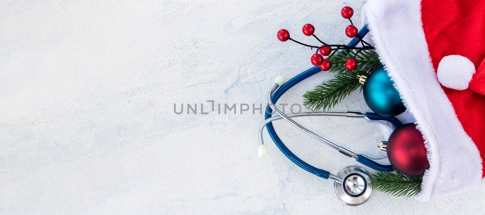 banner with Stethoscope with branches of Christmas tree and Christmas balls in Santa Claus hat. All on white concrete table. Concept Merry Christmas and Happy New year or Healthy New Year. Copy space
