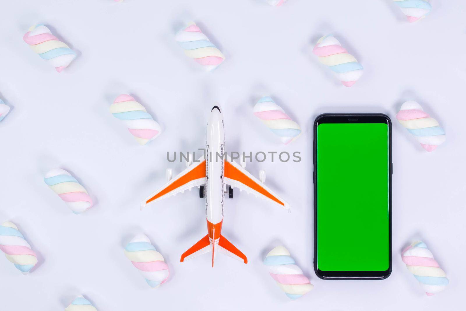 Phone mockup. Airplane model and black smartphone with blank screen. White background with twisted marshmallow pattern.