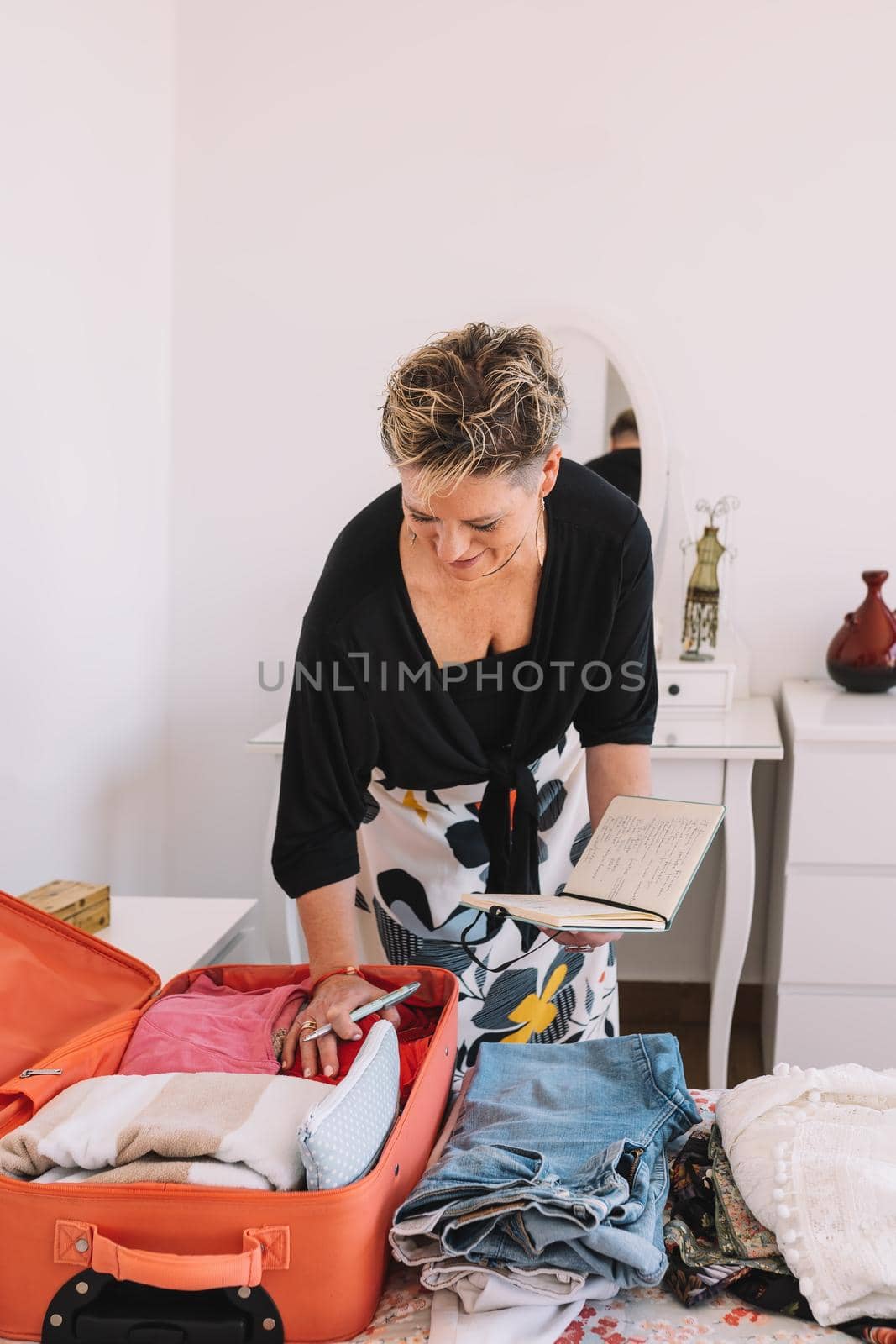 mature woman arriving at the hotel room and unpacking her luggage. summer trip, weekend. concept leisure and hobby. natural light, clean and uncluttered atmosphere.