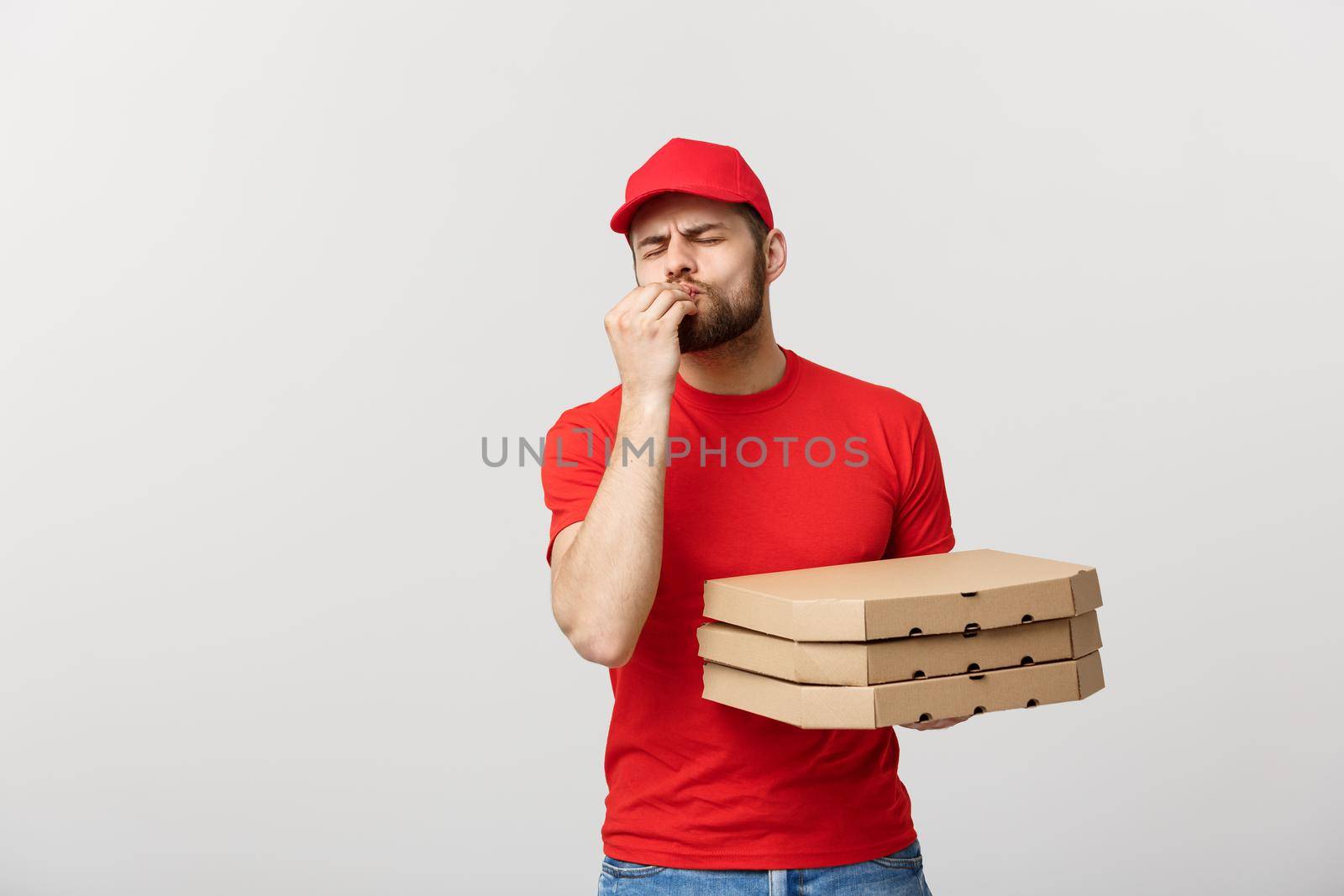 Delivery Concept: Handsome Pizza delivery man showing delicious expression over grey background.