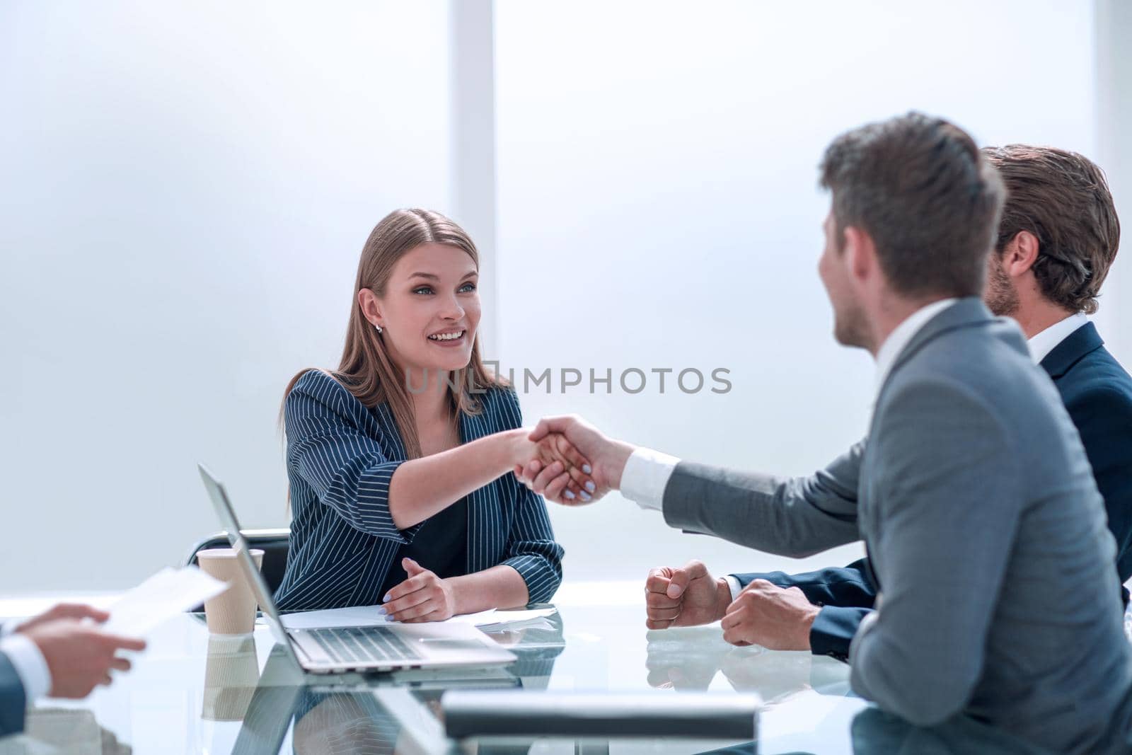 businessman shaking hands with businesswoman sitting at the negotiating table . concept of partnership