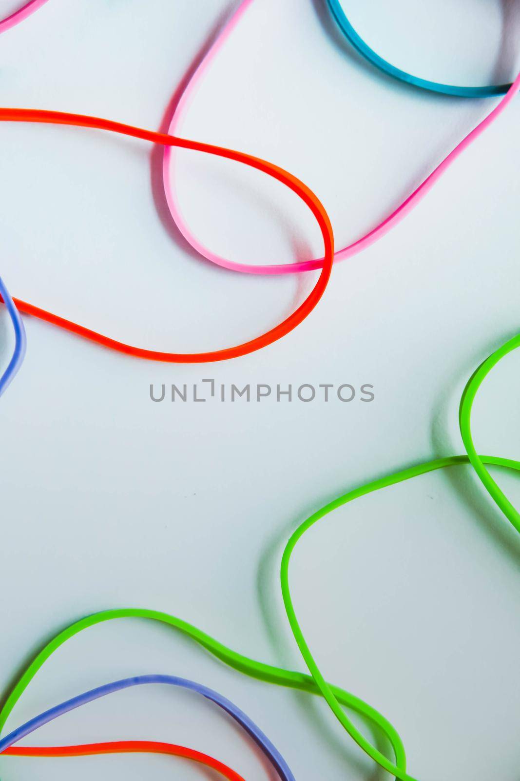 Top view of colorful rubber bands isolated on white. Rainbow elastic rubber bands on white by JuliaDorian