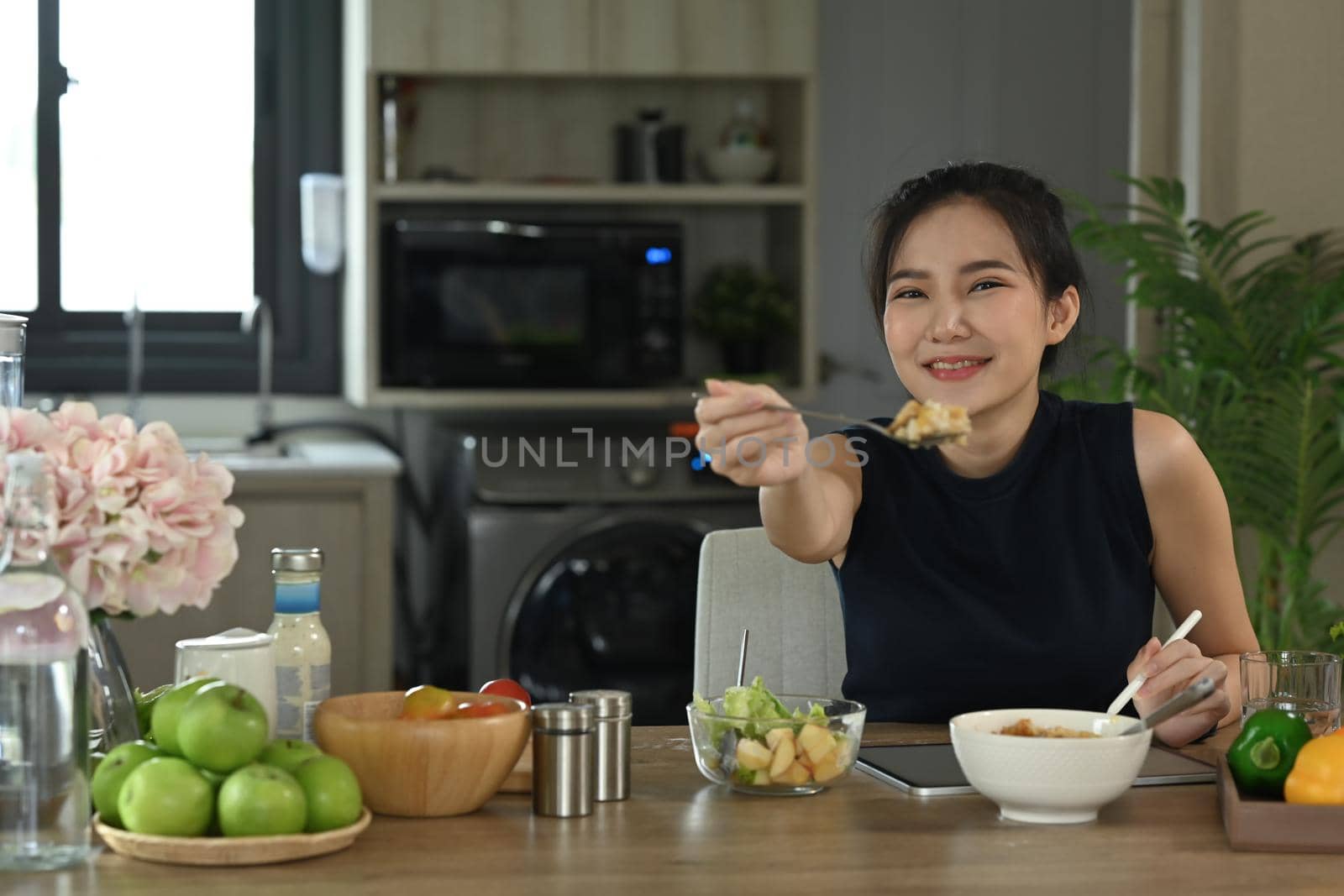 Healthy asian woman sitting at home kitchen and enjoying her vegan meal. Diet and Healthy food concept.