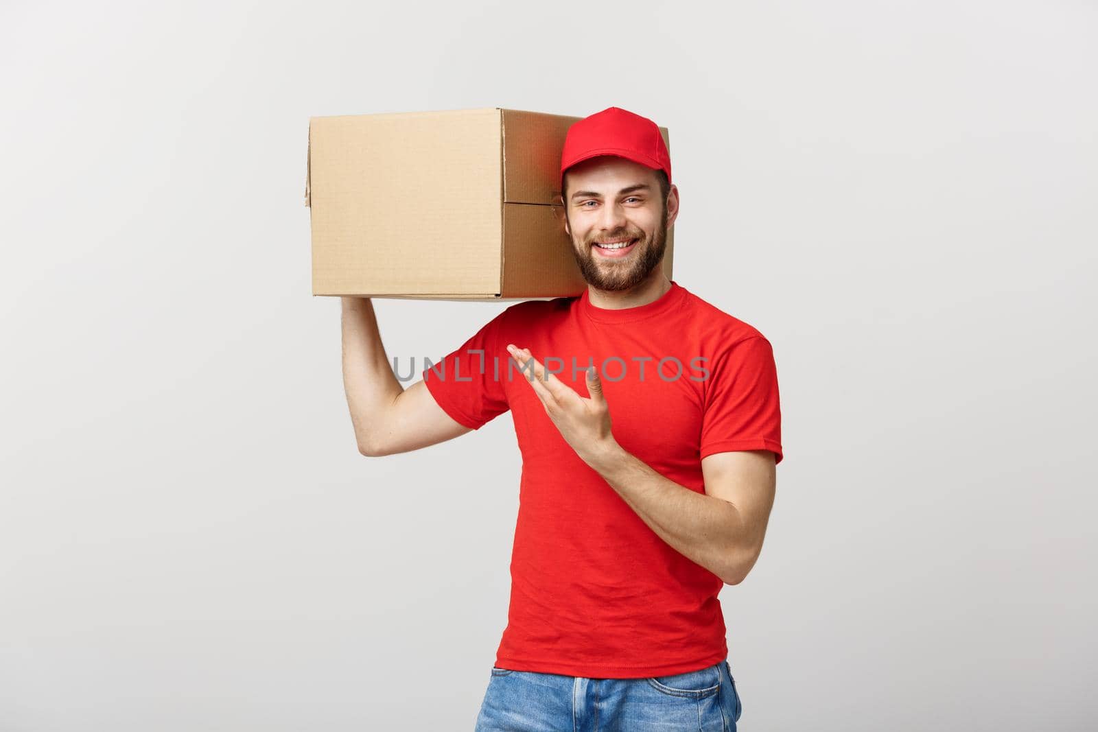 Delivery Concept - Portrait of Happy Caucasian delivery man pointing hand to present a box package. Isolated on Grey studio Background. Copy Space
