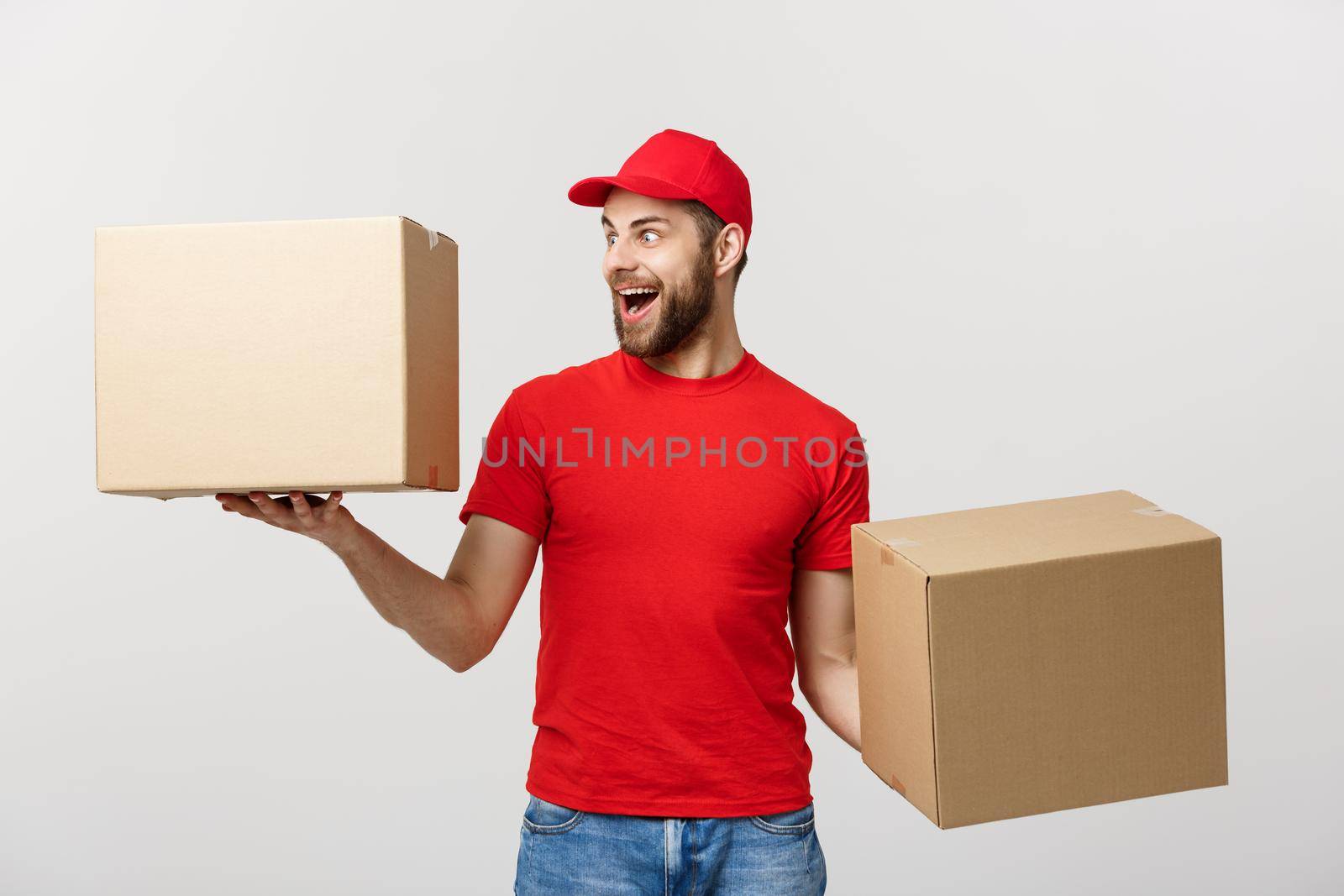 Portrait delivery man in cap with red t-shirt working as courier or dealer holding two empty cardboard boxes. Receiving package. Copy space for advertisement.